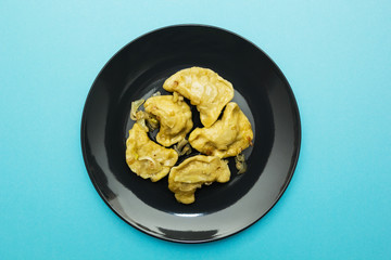 Black plate with pierogies on a blue background.