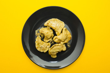 Black plate with pierogies on a yellow background.