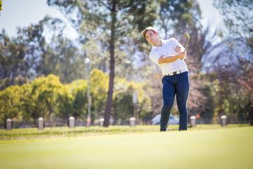 Close up view of a golfer playing a chip shot on a golf course in south africa with back light.