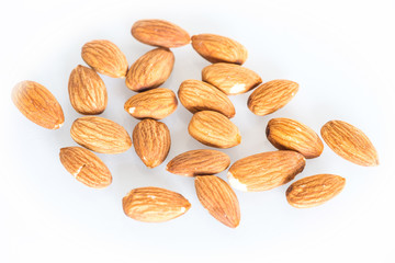 Delicacies almonds scattered on the white background.