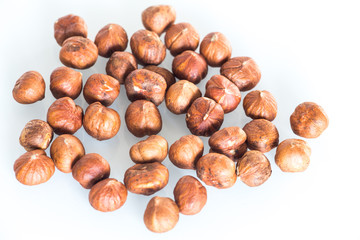 Delicacies hazelnuts scattered on the white background.