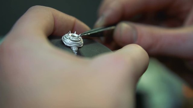 Inlaying a silver ring with precious stones closeup