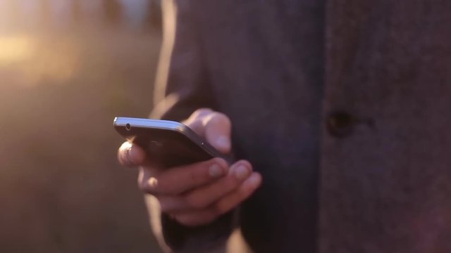 Man Using His Smart Phone On Sunset Close Up