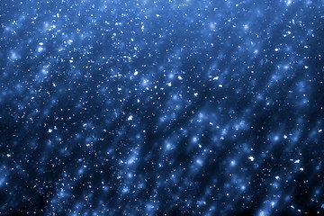 Abstract round blue bokeh or glitter lights on dark background. Circles defocused particles and rays