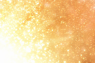 Golden rays and sparkles or glitter lights. Merry Christmas festive background.defocused circle bokeh or particles