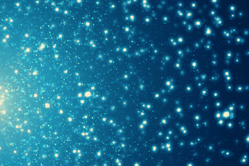 Abstract bokeh glitter lights on blue background. Round defocused circle particles. Christmas template