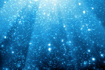 Fototapeta premium Abstract bokeh glitter lights and rays on blue background. Round defocused circle particles. Christmas template