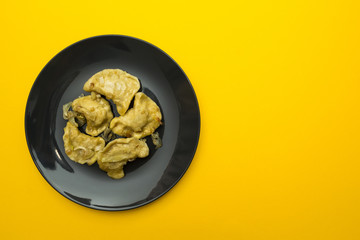 Black plate with pierogies on a yellow background.