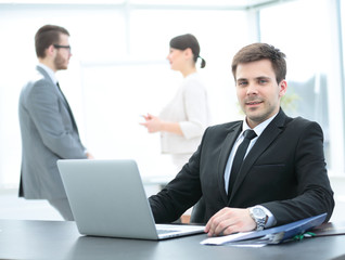 successful businessman sitting behind a Desk with an open laptop