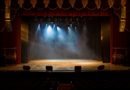 An empty stage of the theater, lit by spotlights and smoke before the performance