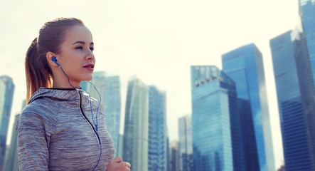 Fototapeta premium happy woman with earphones running in city