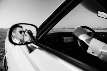 Young loving couple in a cabriolet at sunset