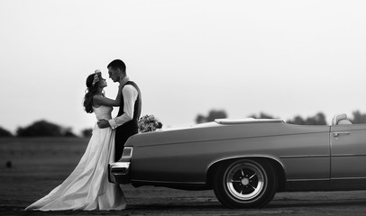 Young loving couple in a cabriolet at sunset