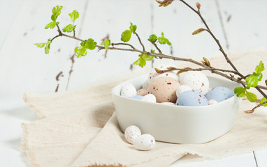 Chocolate Easter Eggs. Natural Linen Textile. Green Spring Leaves. White Wooden Scratched Background.