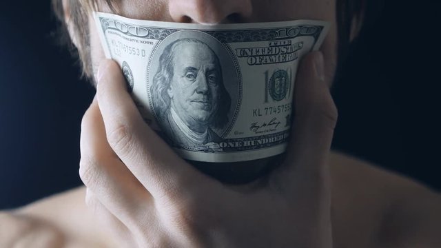 Close up man closes mouth with the hundred-dollar banknote
