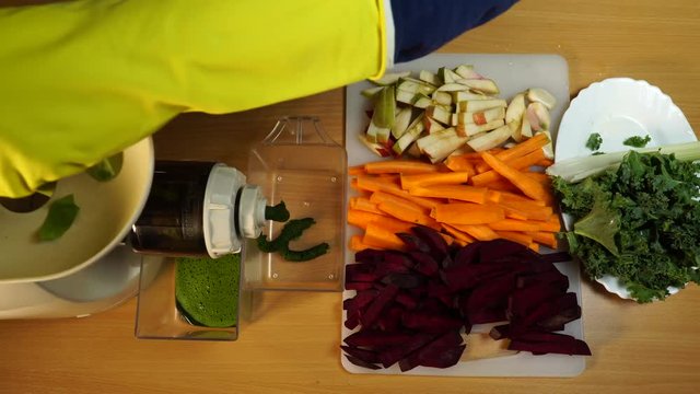 Housewife in kitchen making raw juice, preparing nutritious vitamin packed drink. Healthy eating, vegetarian food, dieting concept.Top view, timelapse 4K ProRes HQ codec