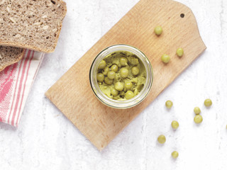 Green peas paste in a jar with wholegrain bread on white background. Flat lay. Top view