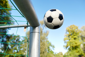 soccer ball flying into football goal net on field
