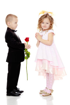The boy gives the girl a flower.