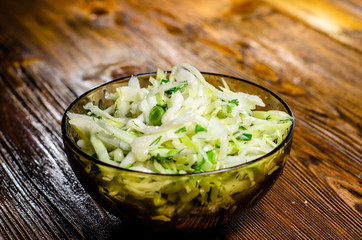Salad with the cabbage and green onion on wooden table