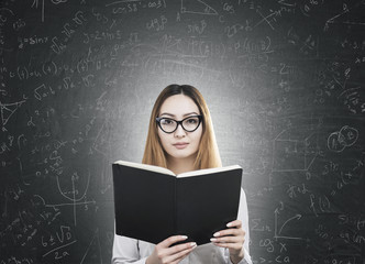 Woman with book near a blackboard