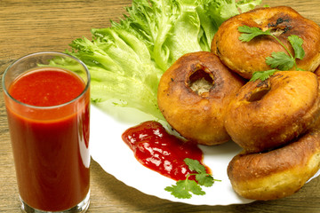 Fried patty on a plate with greens and tomato juice