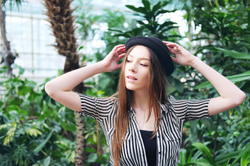 Beautiful long hair girl in hat posing in tropical garden