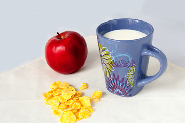 Milk drink with corn flakes and red apple