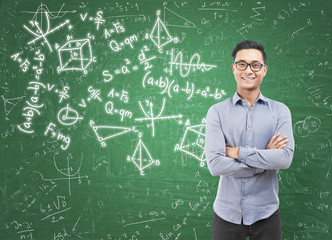 Asian man and formulas on chalkboard