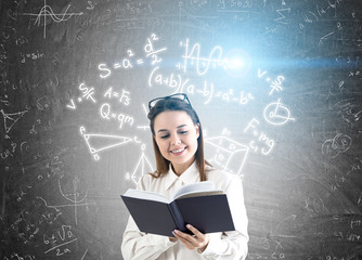 Woman with book and formulas on blackboard