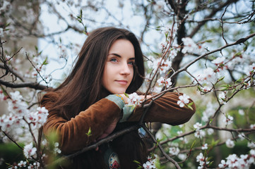Nice girl near a blossom apricot tree in spring