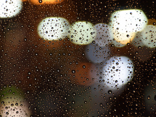 Fensterscheibe mit Regentropfen - Hintergrund mit buntem Licht und Wassertropfen