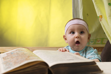 Cute little baby next to a big old book