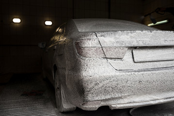 Car wash with soap. Modern car covered by foam. Horizontal photo.