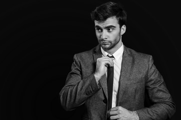 Handsome man adjusting tie, black and white 