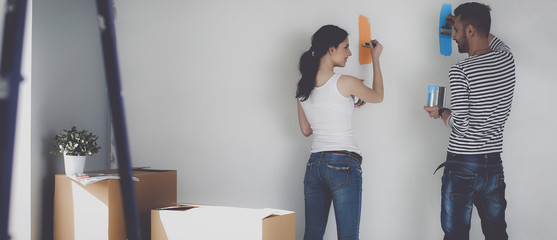 Portrait of happy smiling young couple  painting interior wall of new house