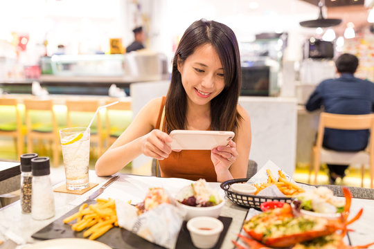 Woman taking photo on dishes in restaurant
