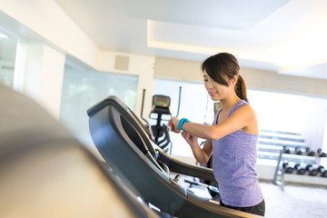 Sport Woman training on treadmill and using smart watch in gym