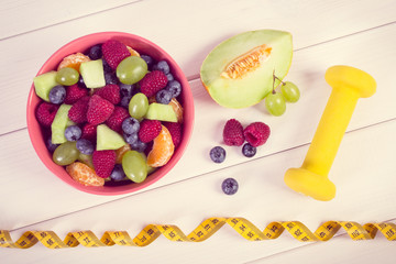 Vintage photo, Fresh fruit salad and centimeter with dumbbells, healthy lifestyle and nutrition concept