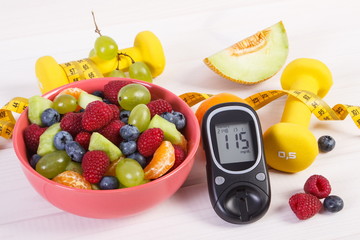 Fresh fruit salad, glucometer, centimeter and dumbbells, diabetes, healthy lifestyle and nutrition concept