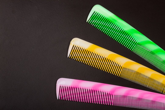 Three different colored hairbrushes on a dark background