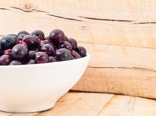 close up to Ribes in white cup on wooden plank background