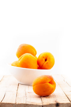 Few fresh peaches in white cup on wooden table