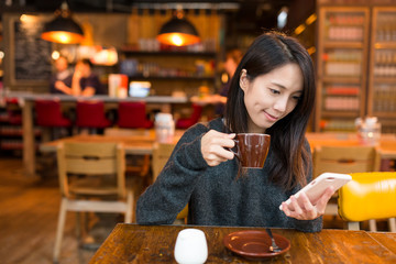 Woman drinking coffee and using cellphone