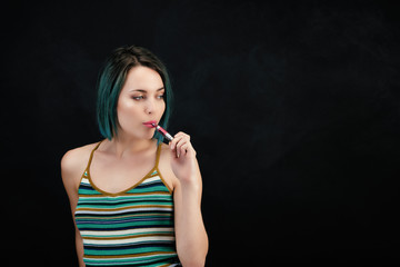 Obraz premium Jeune femme vape une cigarette électronique