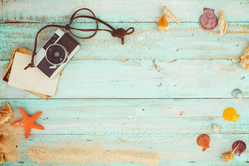 Summer background - The concept of leisure travel in the summer on a tropical beach seaside. retro camera with starfish, shells, coral on wood table background.  vintage color tone styles.