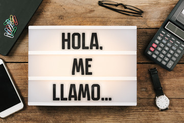 Hola, me llamo…, Spanish text for Hello, My Name is... in vintage style light box on office deskt...
