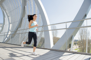 young beautiful athletic sport woman running and jogging crossing modern metal city bridge