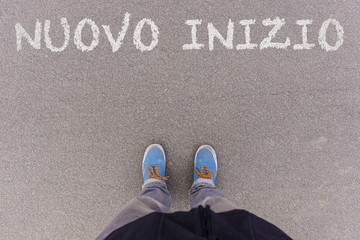 Nuovo inizio, Italian text for New Beginning text on asphalt ground, feet and shoes on floor