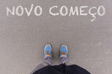 Novo comeco, Portuguese text for New Beginning text on asphalt ground, feet and shoes on floor